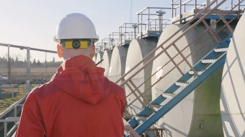 Back side close up petrochemical engineer walks along row of cisterns with oil Stock Footage 109532070