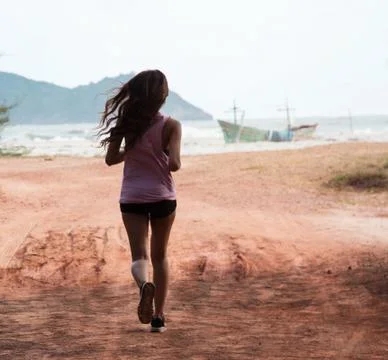 The back side of lady in exercise suit is jogging on the beach,in the morning Foto stock
