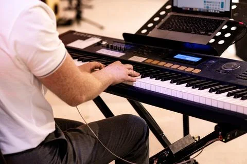 From the back side of a man's hand playing an electric piano at a concert Stock Photos