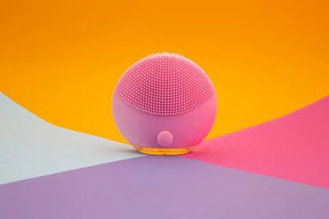 Back side of mini pink silicone facial cleansing brush on colorful background Stock Photos