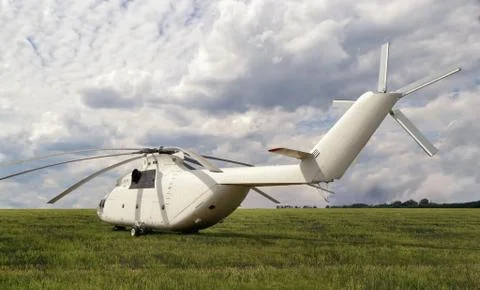 Back-side view of big white cargo helicopter parked at field with green grass Stock Photos