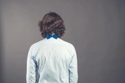 Back side view of a man with dark shaggy curly hair wearing blue shirt and bow Stock Photos
