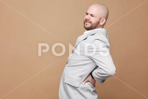 Back spine pain. Profile side view portrait of middle aged bald bearded busin Stock Photos