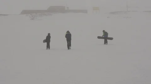 Back static shot of three snowboarder walking in the snow, during foggy day Stock Footage 121202790