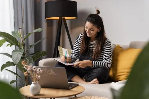 Back to study. Happy student making notices in notebook taking classes at home Stock Photos