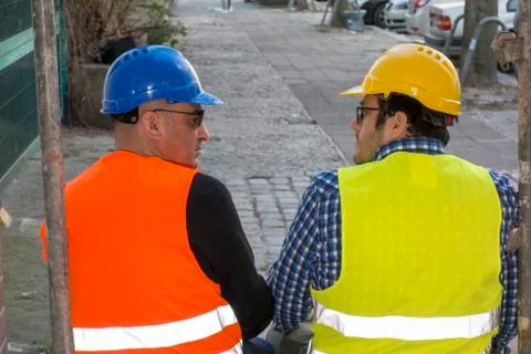 Back turned construction workers sitting and talking Stock Photos
