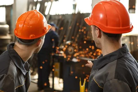 Back of two workers looking at process of welding on metal stock Stock Photos