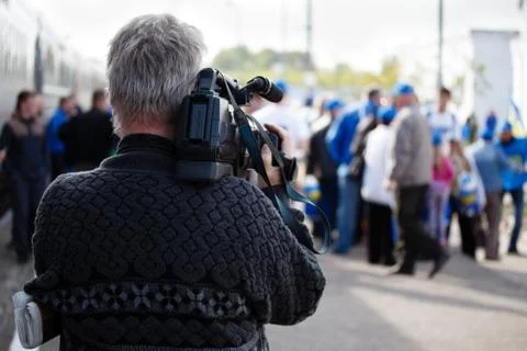 Back of videographer takes video camera and blur image of people in the bac.. Stock Photos