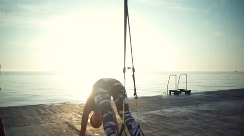 Back view of 3 persons work out with TRX near the sea slow motion Video stock 67991817