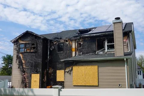 Back view of an abandoned fire damaged house with boarded windows and and d.. 库存照片