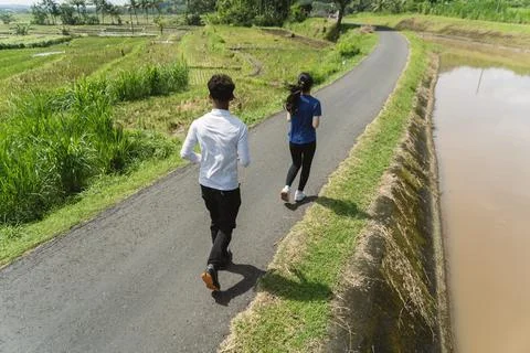Back view of active asian couple jogging exercise at rural area Stock Photos