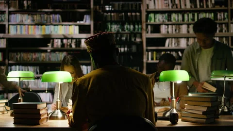 Back view of adult learner in traditional clothes at dark library table Stock Footage 337229975