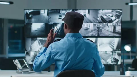 Back view of African American security officer in system control room answer Stock Footage 180443757