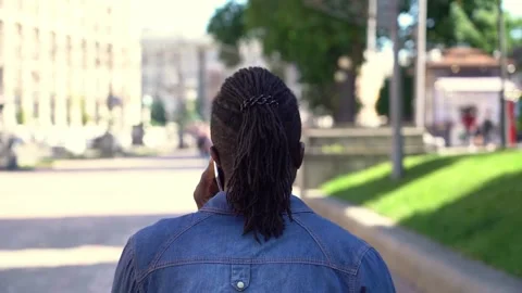 Back view of African hipster man walking on the street talking on mobile phone Stock-Footage 157766788