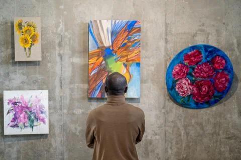 Back view of African male guest of art gallery standing in front of wall with Stock Photos
