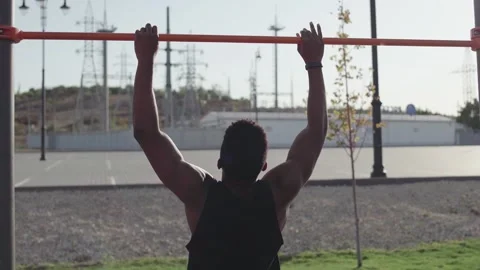 Back view of african man doing pull ups on horizontal workout outdoors Stock Footage 143501051