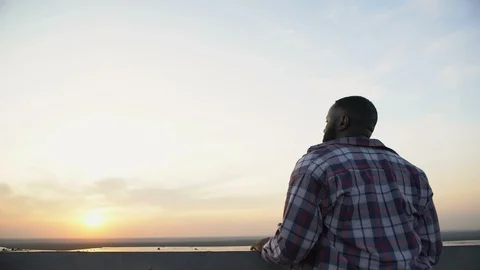 Back view of Afro-American man enjoying sunset from roof top, day dreaming Stock Footage 117219348