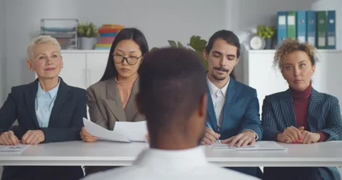Back view of afro-american man at job interview talking to four elegant members Stock Footage 154151351