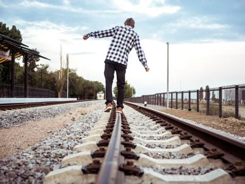 Back view of alone man catching balance on the railway track Stock Photos
