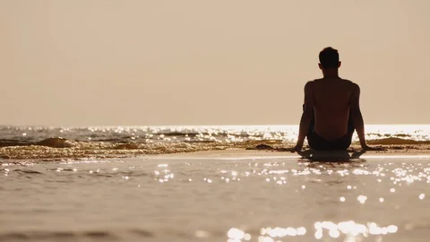 Back view of alone young man sitting on a small sand island Stock Footage 128893867
