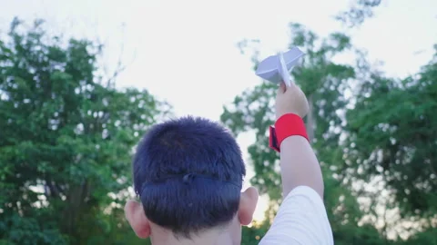 Back view of Asian boy walking and playing paper rocket in the park Stock Footage 173355801