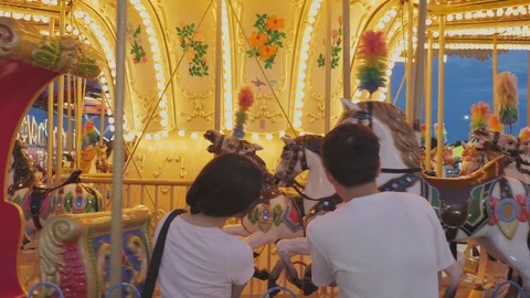 Back view of Asian couple looking Carousel near fence while dating with roman Vídeo Stock 124323874
