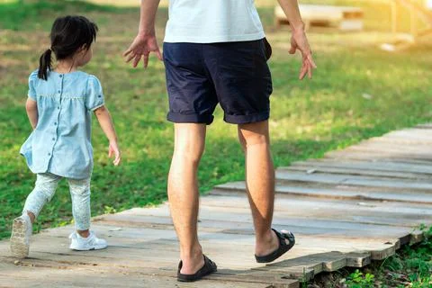 Back view of Asian father take care his lovely daughter walking on pathway th Stock Photos
