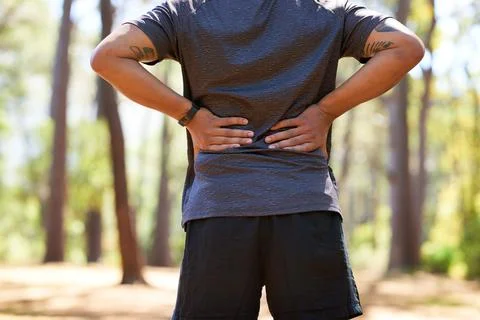 Back view of Asian man with hands on lower back, muscle pain taking a break Stock Photos