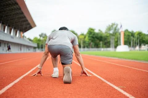 Back view of an Asian runner in starting position ready to run on racetrack.. Stock Photos