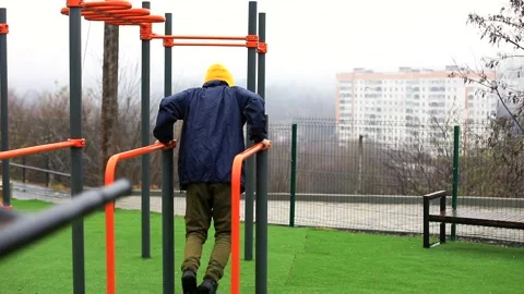 Back view of athlete man doing exercises on pull-up horizontal bar outside enjoy 스톡 동영상 166090469