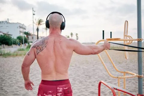 Back view of an athlete man doing calisthenics workout with a resistance rubber Stock Photos
