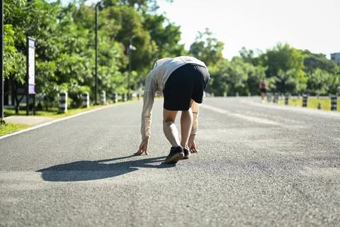 Back view of athlete in a starting position on the ground ready to sprint Stock Photos