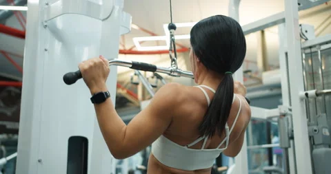 Back view of athletic girl in white top doing back muscle exercises on block Stock Footage 306235448