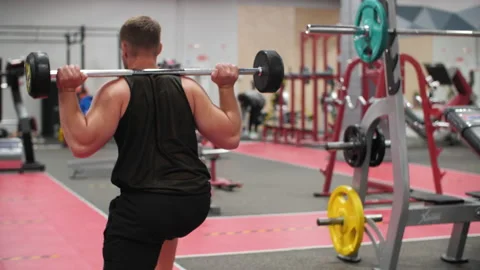 Back view of athletic man doing lunges with barbell on shoulders Stock Footage 136716817