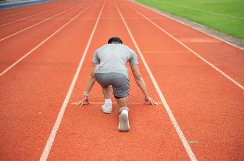 Back view of athletic man ready to sprint from starting position on running.. Stock Photos