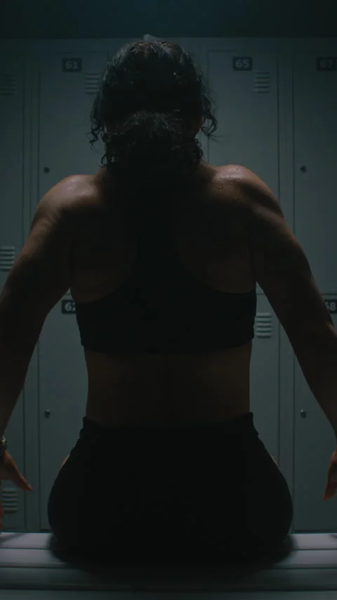 Back View of Athletic Woman Stretching Muscles After Workout in Locker Room Stock Footage 335393865