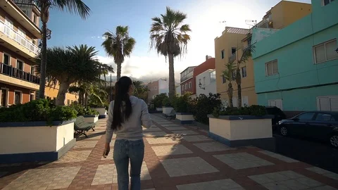 Back view of attractive long-haired curly brunette woman walking down the city Stock Footage 119288569