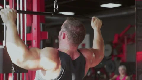 Back view of an attractive man bodybuilder performing Lat pulldown at gym Stock Footage 143521290