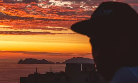 Back view backlight portrait of a single men watching a sunset on the sea with a Stock Photos