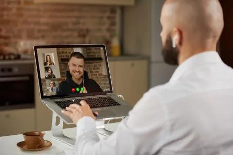 A back view of a bald guy with a beard who is working remotely on laptop at h Stock Photos