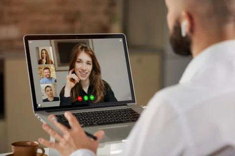 A back view of a bald guy with a beard who is working remotely on laptop at h Stock Photos