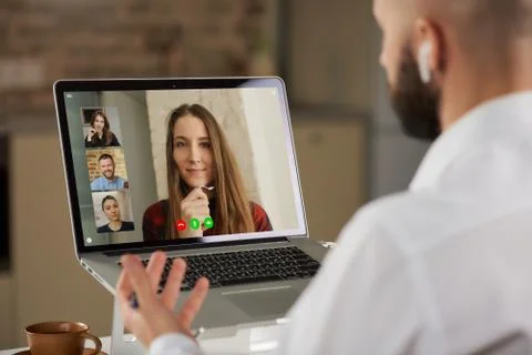 A back view of a bald guy with a beard who is working remotely on laptop at h Stock Photos