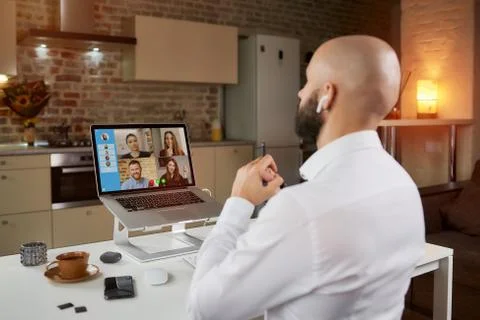 Back view of bald man with beard who is working remotely on a video conferenc Stock Photos