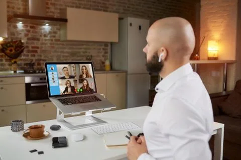 Back view of bald man with beard who is working remotely on a video conferenc Stock Photos