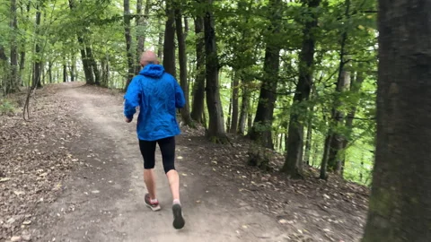 Back view of bald man running by forest trail in Slovakian mountains. Runner is Video stock 317959237