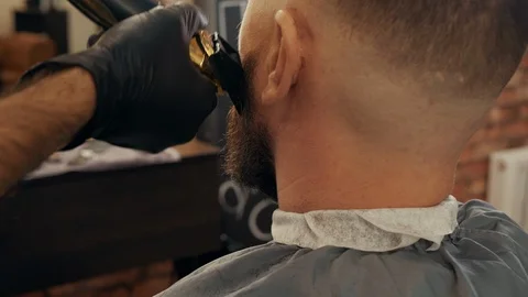 Back view of barber trimming beard of client Stock Footage 125131342
