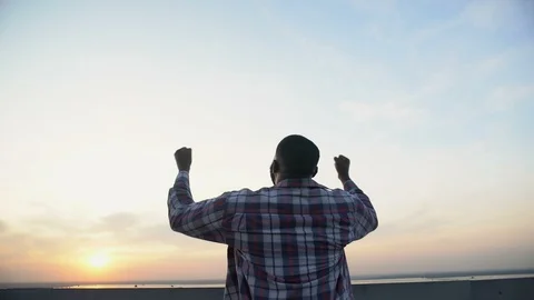 Back view of black man raising hands to sky against sunset, achievement, winner 動画素材 117218240