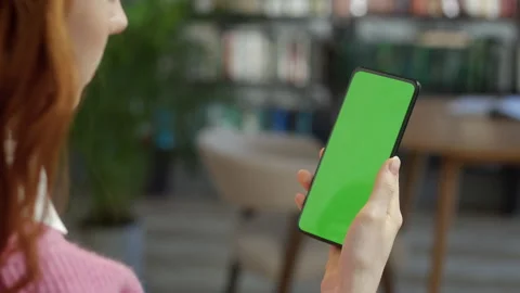 Back View of Blond Man Holding Chroma Key Green Screen Smartphone Watching Stock Footage 205586043