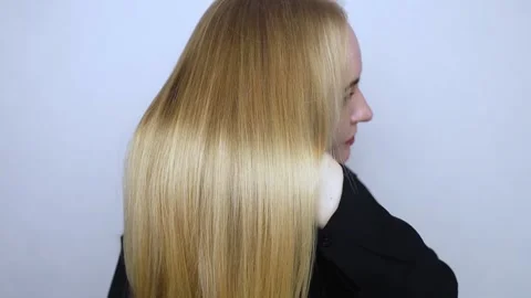 Back view. Blonde runs a comb through her straight golden hair. Hair care concep Stock Footage 302257465