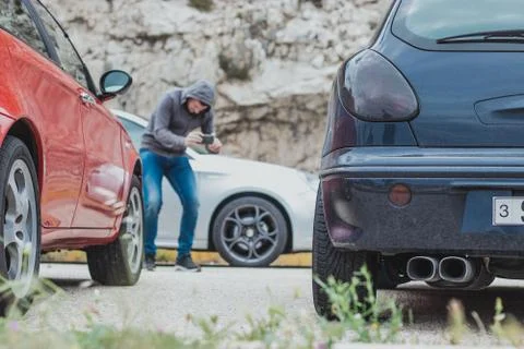 Back view of a blue modified car with two exhausts, man in the distance blurr Stock Photos